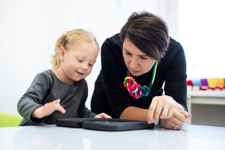 AI-Powered Autism Therapy: Female therapist using a tablet with a girl.