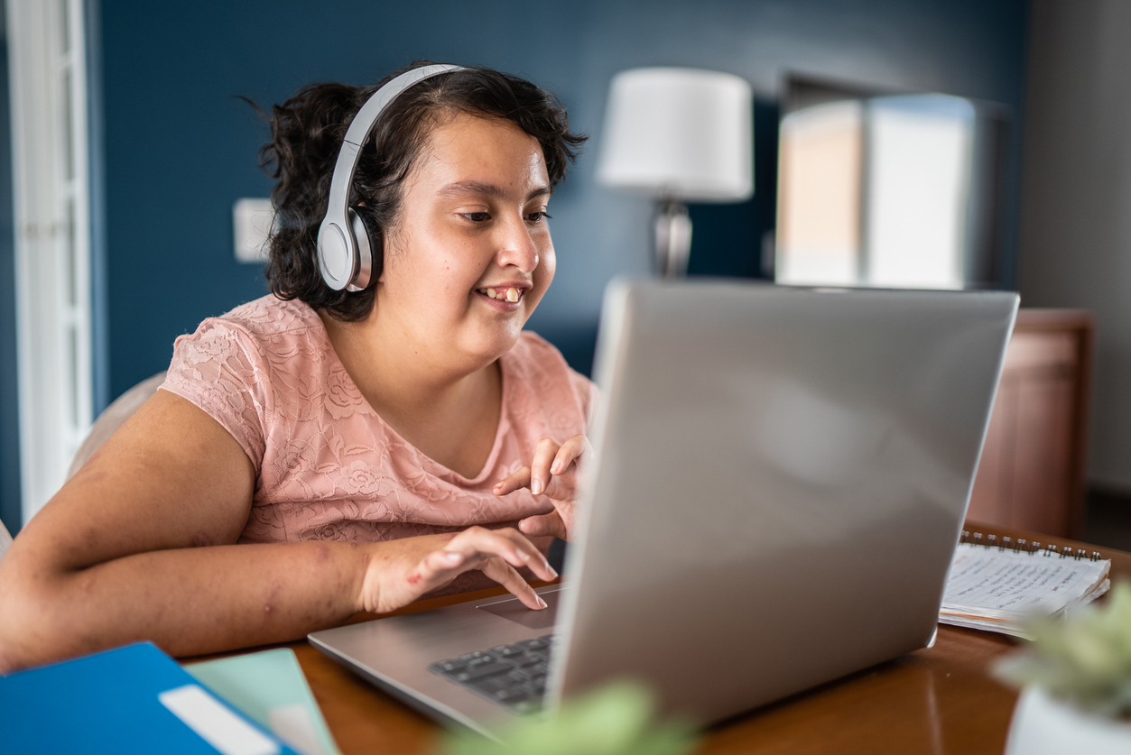 Autism as a challenging behavior: Child with autism using a laptop while wearing a headset in a room.
